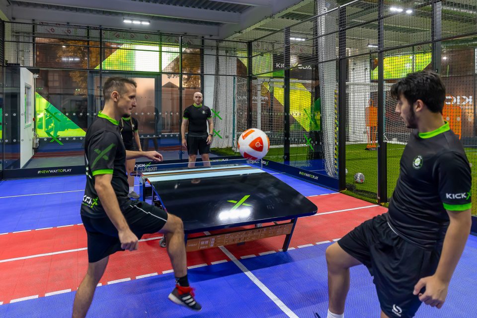 4 players playing 2v2 Teqball, a hybrid of football and table tennis